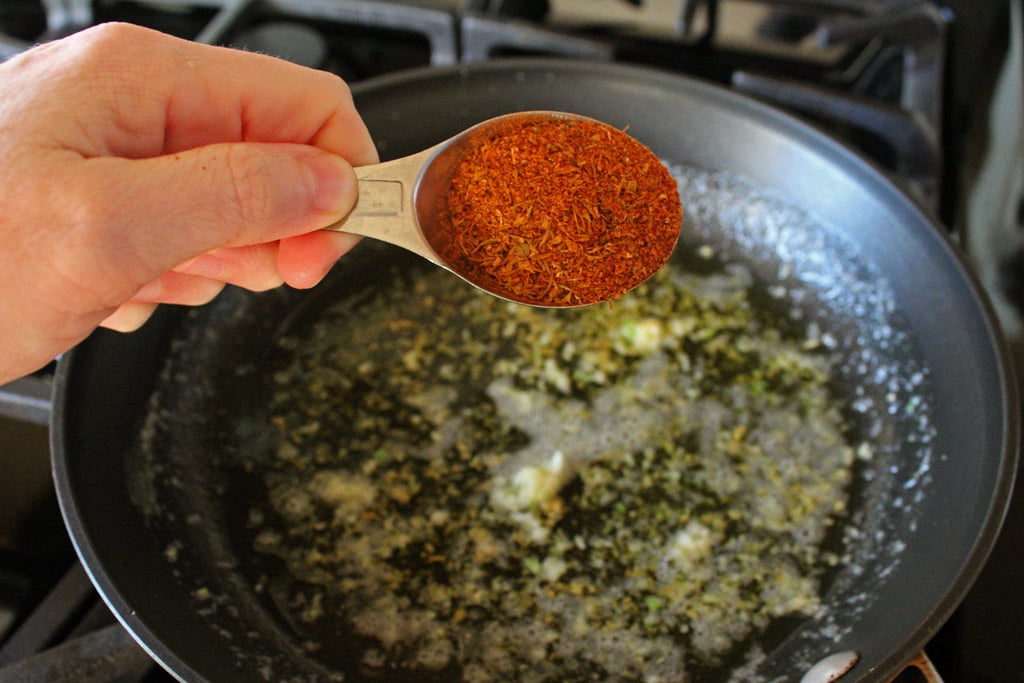 spooning Cajun seasoning into skillet
