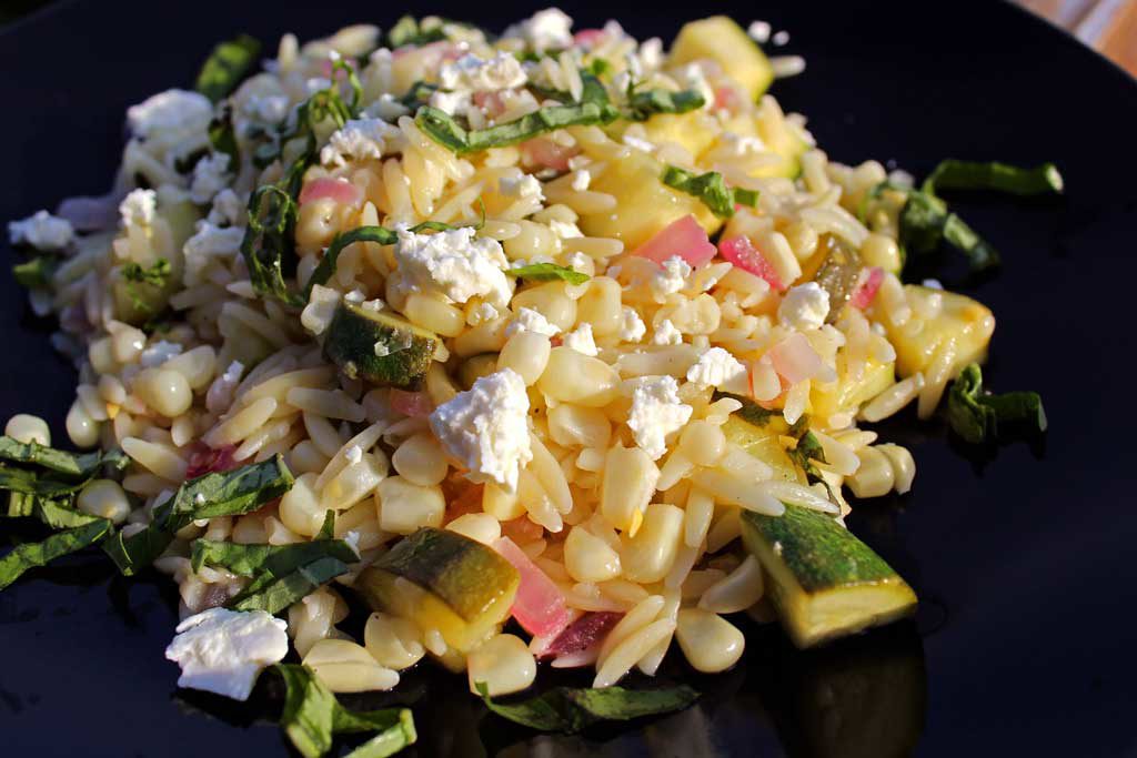 Summer is bursting with flavor in this corn zucchini orzo salad. Seasonal vegetables combined with lemony orzo and feta cheese for a quick pasta salad. Yum! | TheMountainKitchen.com