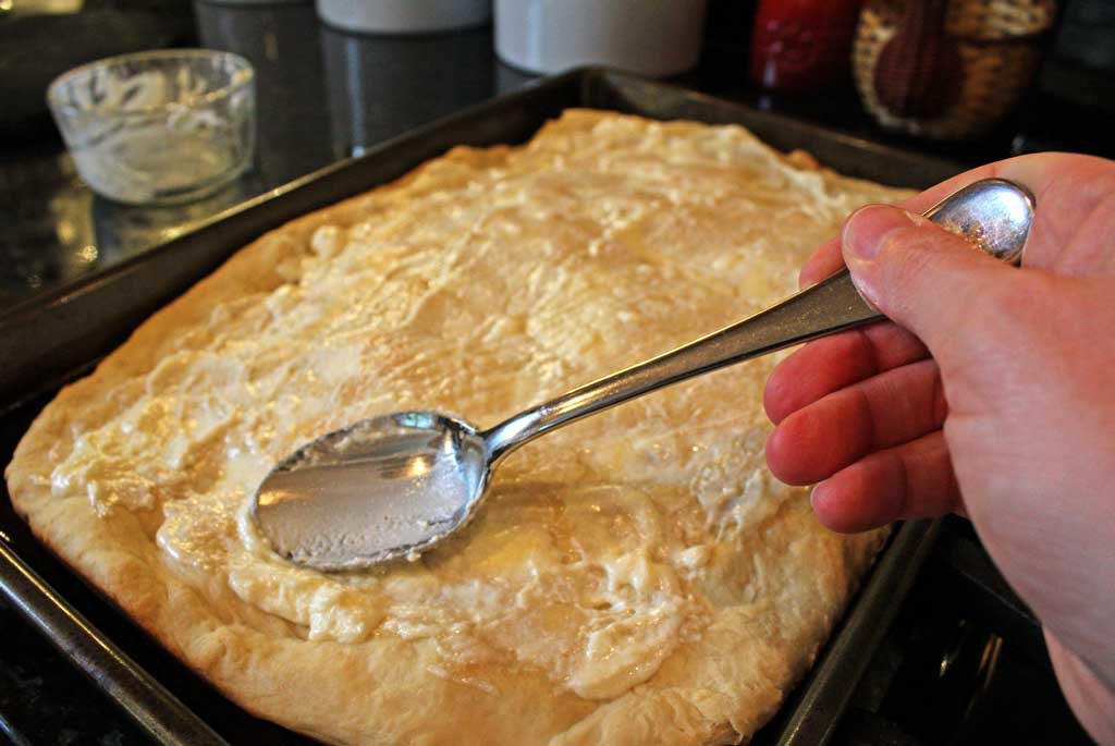 spreading ricotta cheese onto dough