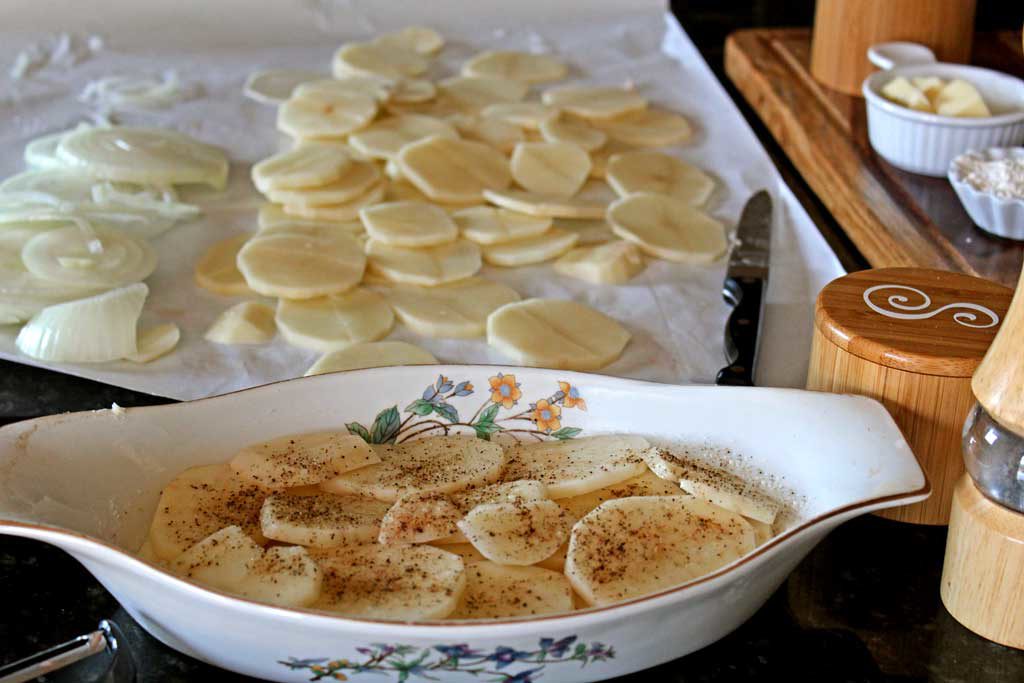 sliced potatoes and onions in casserole dish