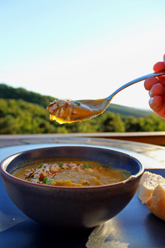roasted pumpkin soup in bowl with hand holding spoonful