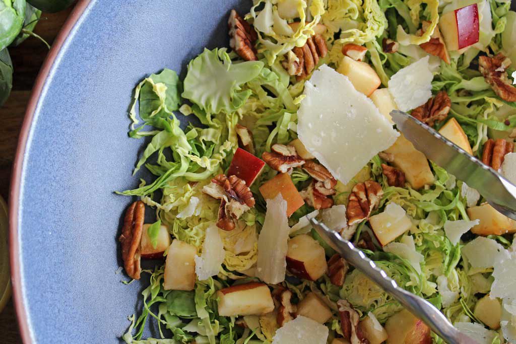 This apple pecan brussels sprout salad is for crunch lovers! Made with shredded brussels sprouts, apples, pecans, parmesan cheese and homemade dressing. | TheMountainKitchen.com