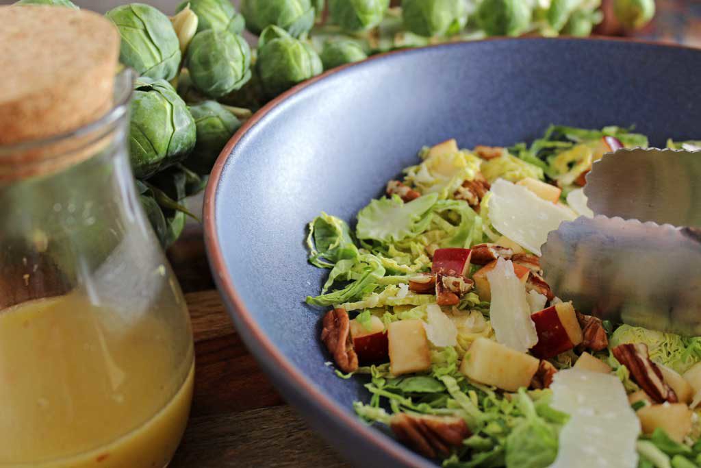 This apple pecan brussels sprout salad is for crunch lovers! Made with shredded brussels sprouts, apples, pecans, parmesan cheese and homemade dressing. | TheMountainKitchen.com