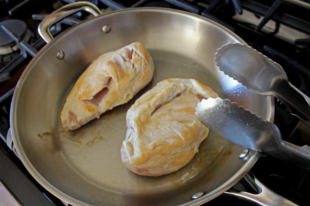 chicken breasts browning in pan