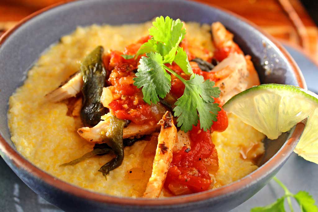 Spicy chicken poblano stew with polenta puts a Mexican spin on Italian food. With only 389 calories per serving, this hearty weeknight dish is made of shredded chicken, stewed with smoky poblanos, and onions in a garlicky tomato sauce spiced up with adobo sauce, served over creamy sweet porridge of polenta. | TheMountainKitchen.com