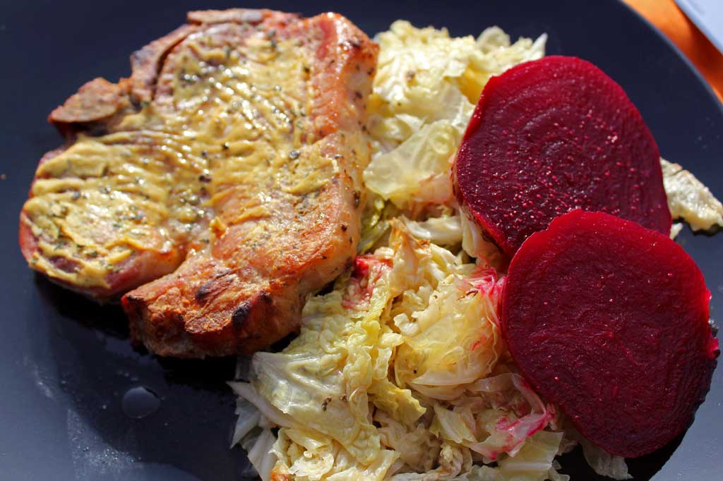 Dijon pork chops dredged in lemony Dijon mustard with herbs, roasted on a bed of cabbage in a rich broth. Try with roasted beets with apple cider vinegar! | TheMountainKitchen.com