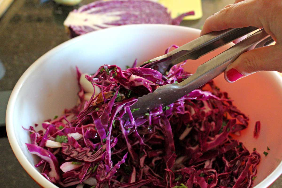 tossing the red cabbage slaw