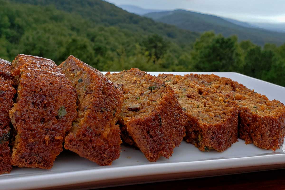 Slices of zucchini bread on a platter with the mountains in the background.