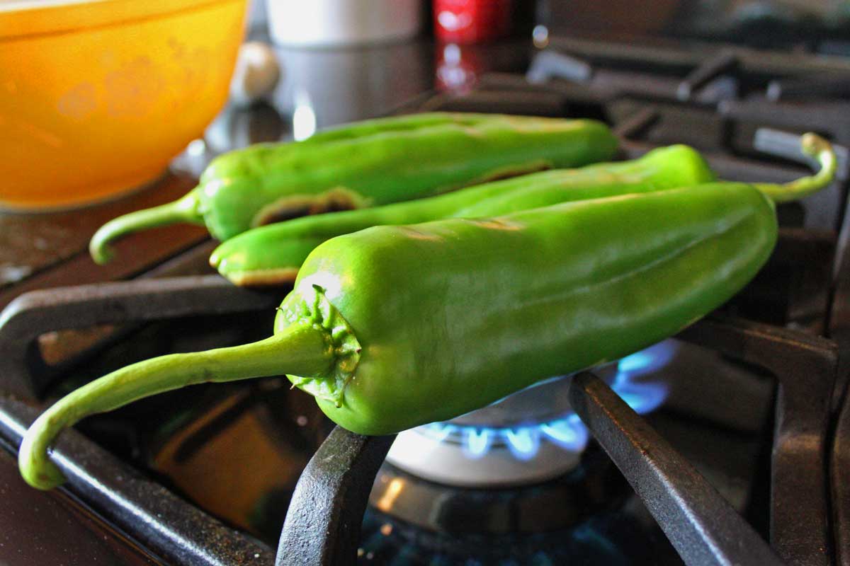 hatch chili roasting over gas stove flame