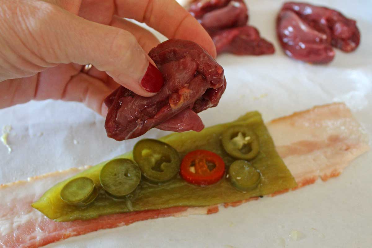 bacon strip covered in chilies and garlic with hand placing dove breast