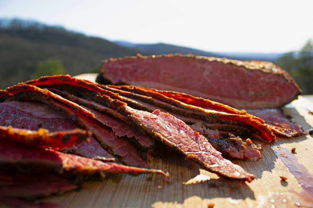 sliced pastrami on cutting board with mountain view