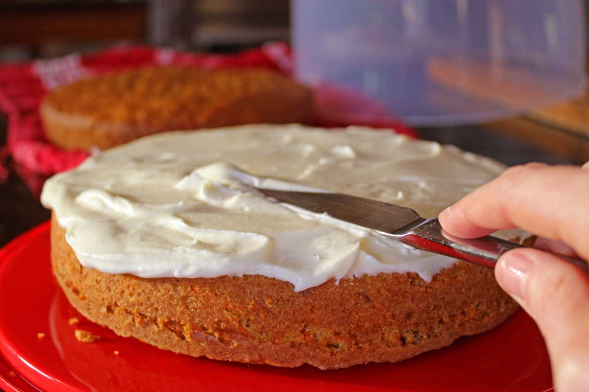 spreading icing on ultimate carrot cake