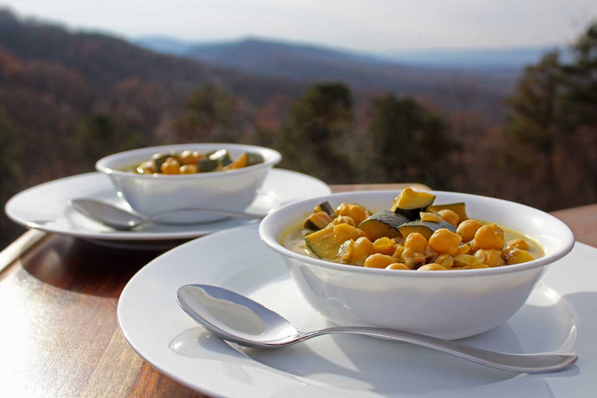 Two bowls of stew with a view of the mountains in the background.