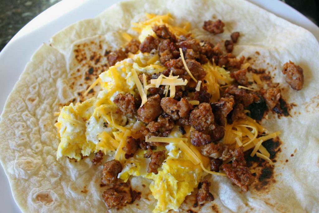 a flat tortilla topped with egg, sausage and cheese