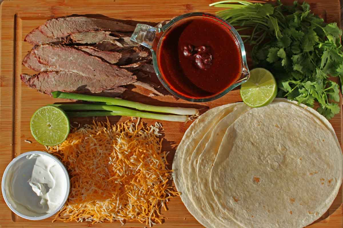 Leftover brisket? Make this recipe for smoked beef brisket enchiladas! Smoky brisket wrapped in tortillas smothered in enchilada sauce and gooey cheese.