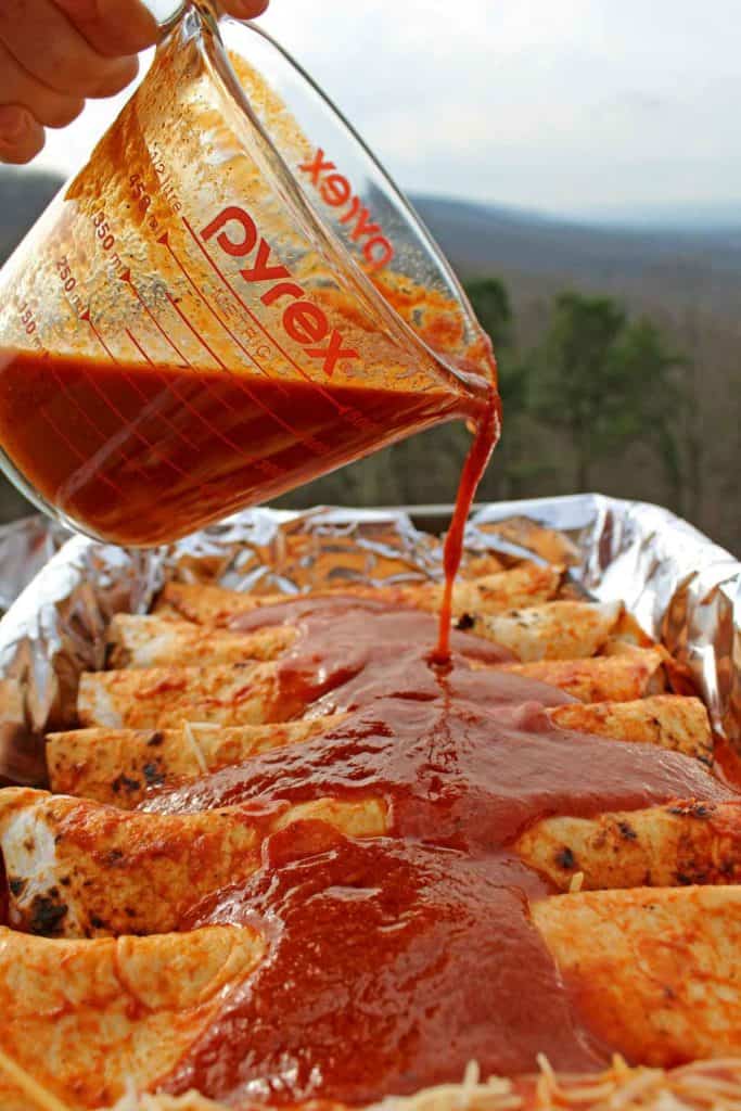 pouring enchilada sauce over brisket enchiladas