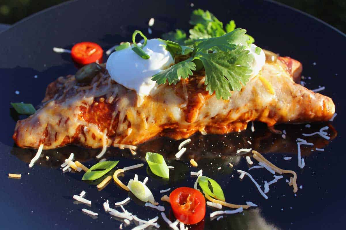 Leftover brisket? Make this recipe for smoked beef brisket enchiladas! Smoky brisket wrapped in tortillas smothered in enchilada sauce and gooey cheese.