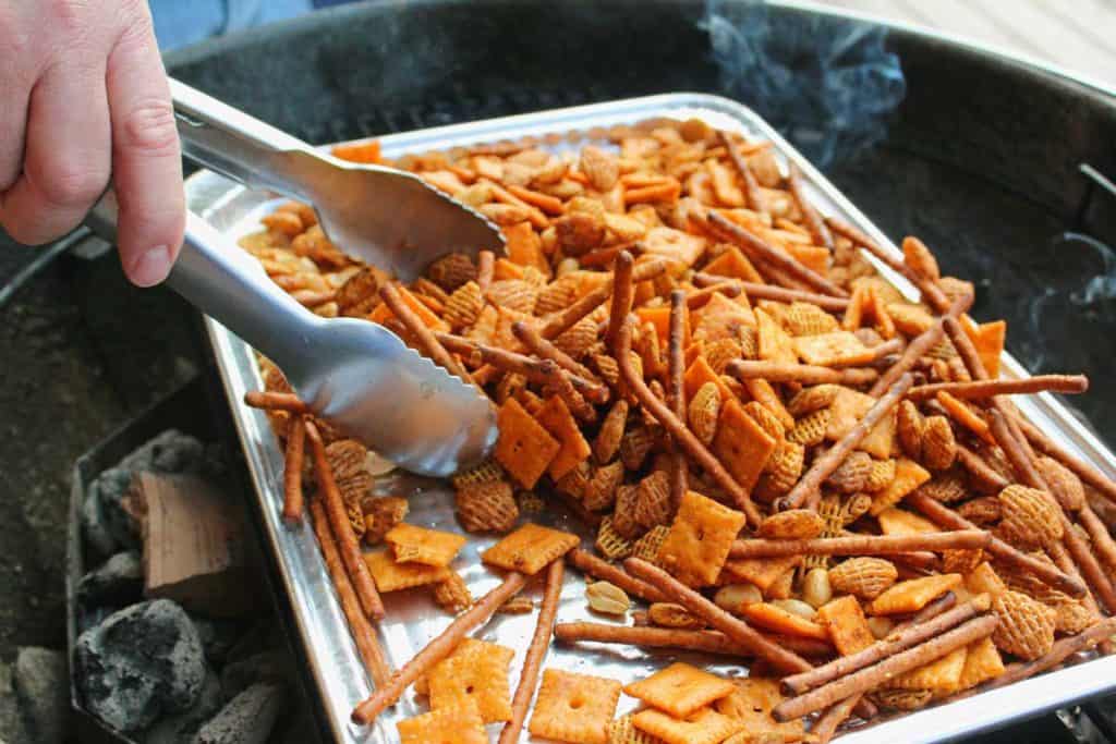 tossing the snack mix with tongs