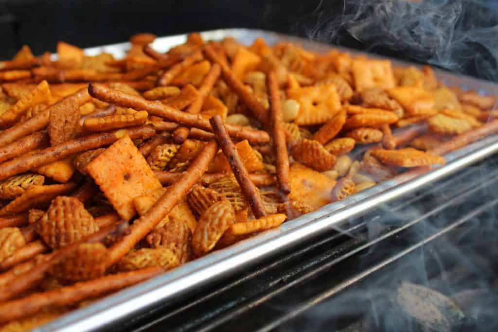 smoke kissing the snack mix on the grill