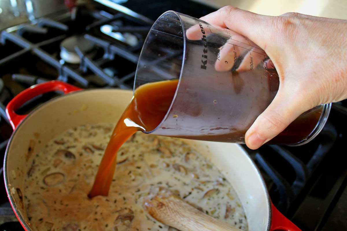 pouring vegetable broth into a pot