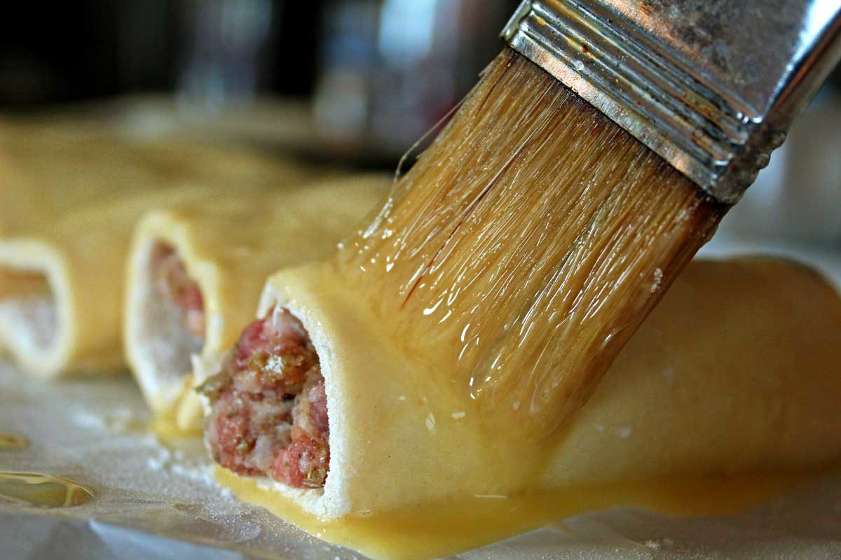 brushing egg wash onto a sausage roll
