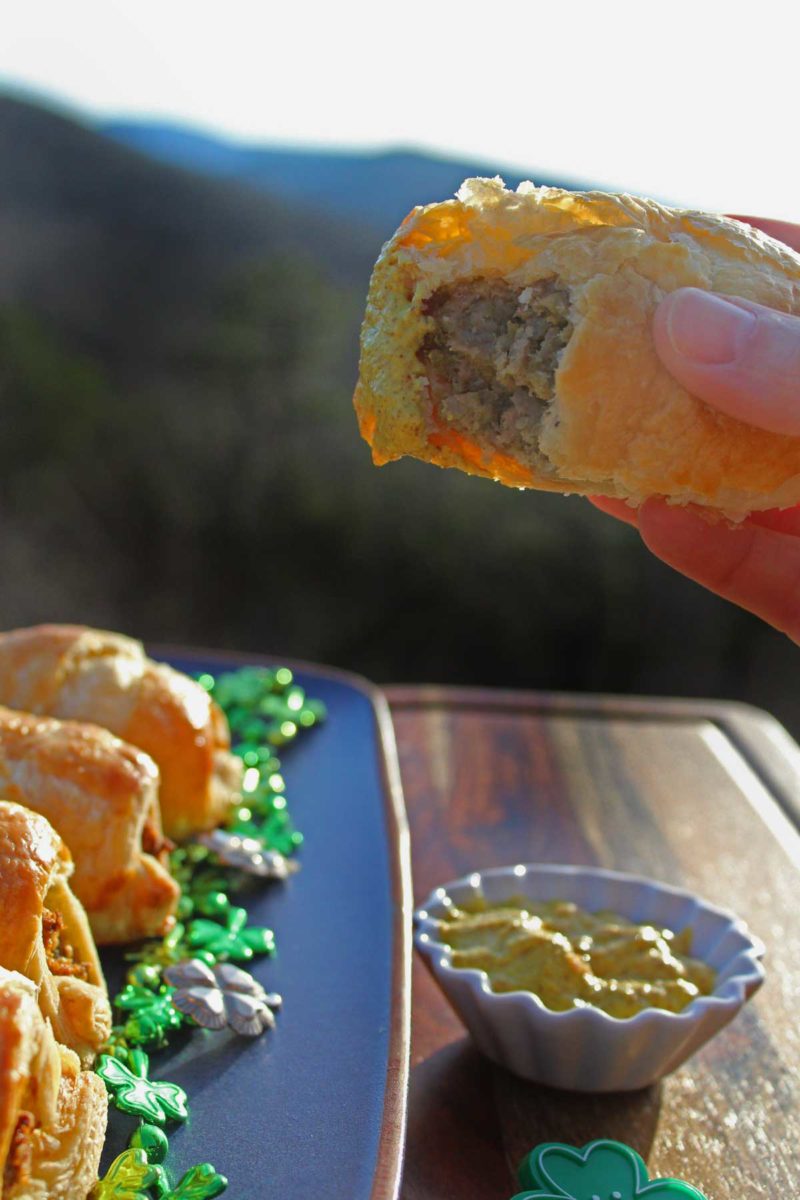 dipping a sausage roll into mustard