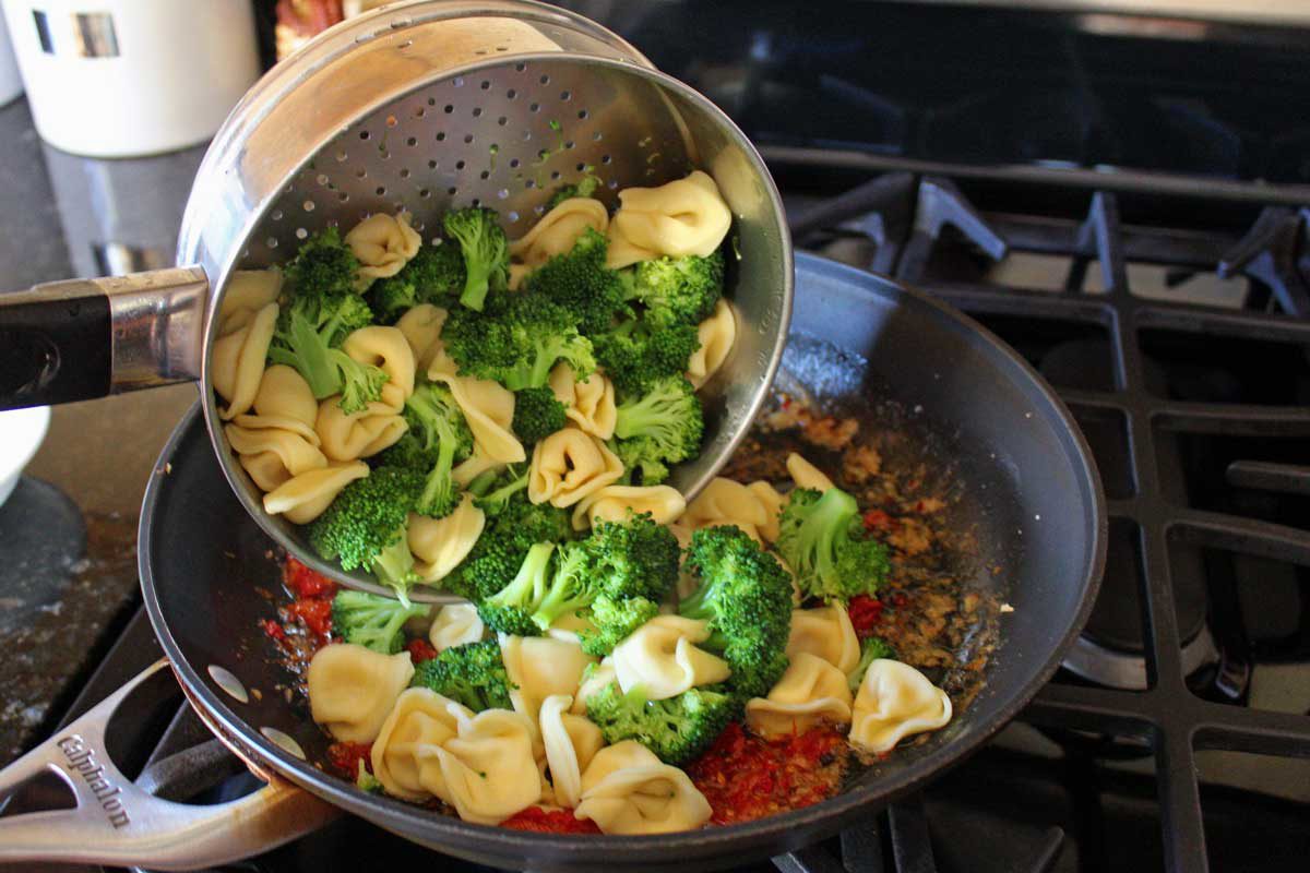 adding the broccoli and tortellini to the pan