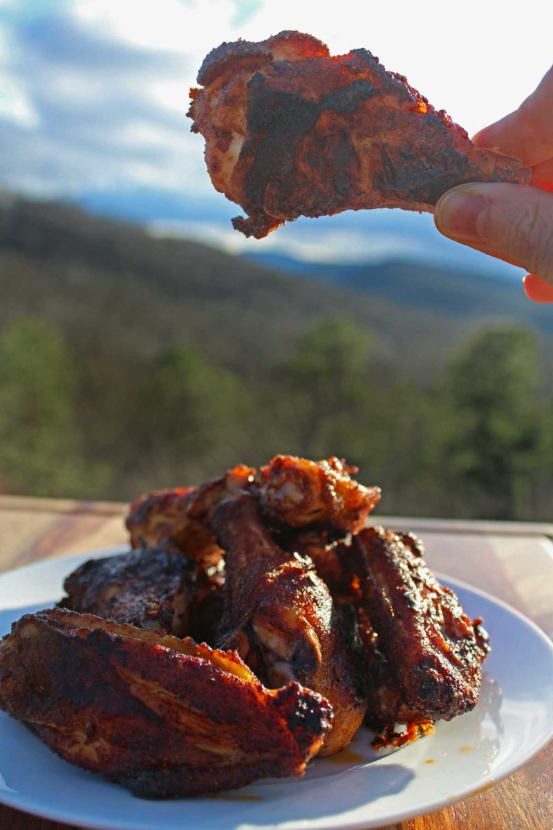 holding up baked chicken wing of plate piled up with them