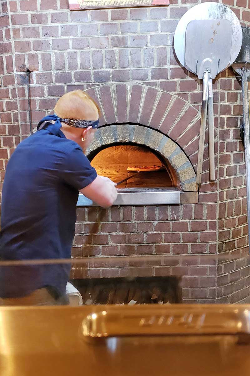 guy tending to pizza oven