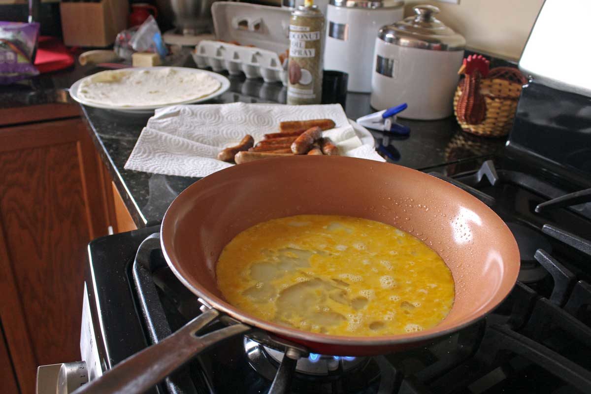 a skillet with eggs cooking on stove