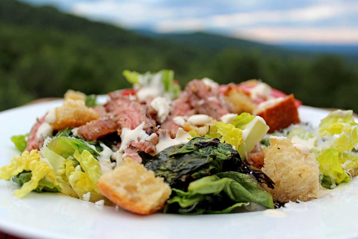 plate of grilled steak Caesar salad with mountain view