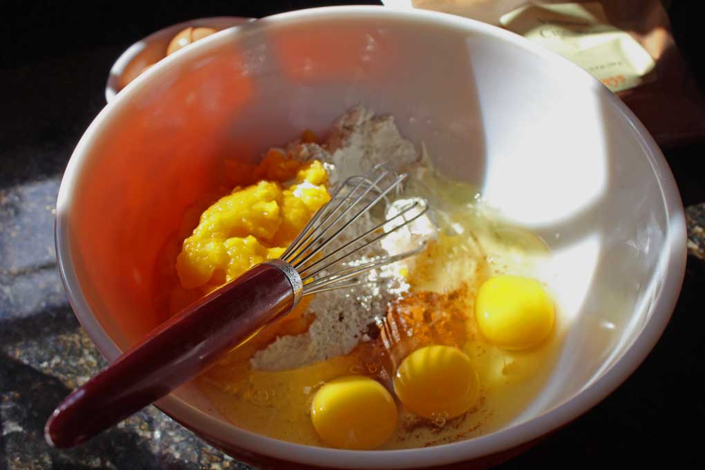 pumpkin roll ingredients in mixing bowl with whisk