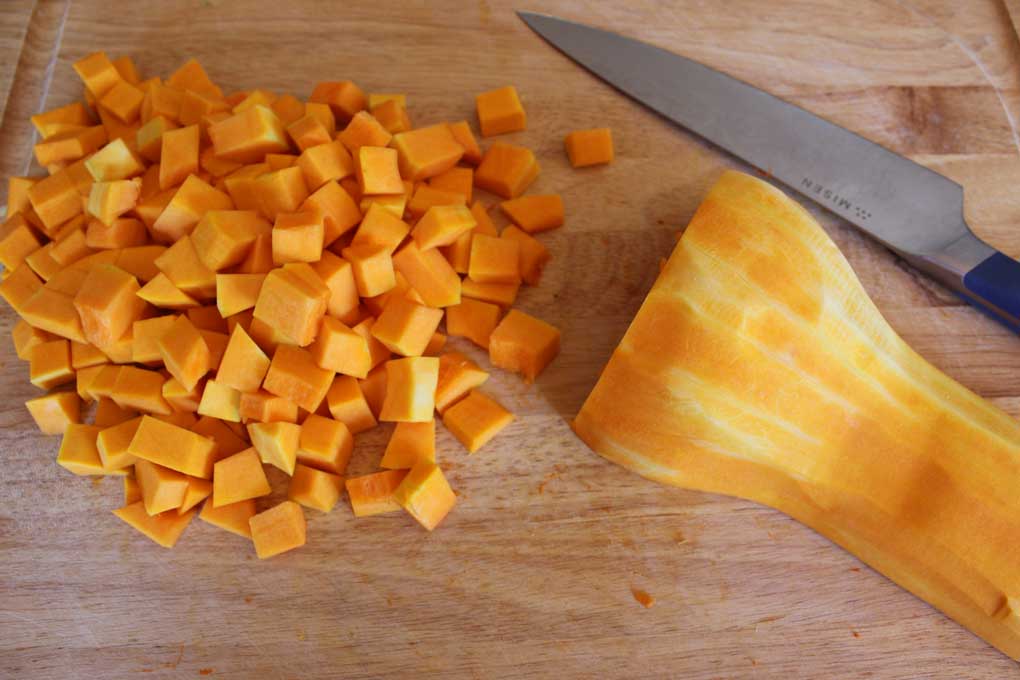 cut butternut squash on cutting board with knife