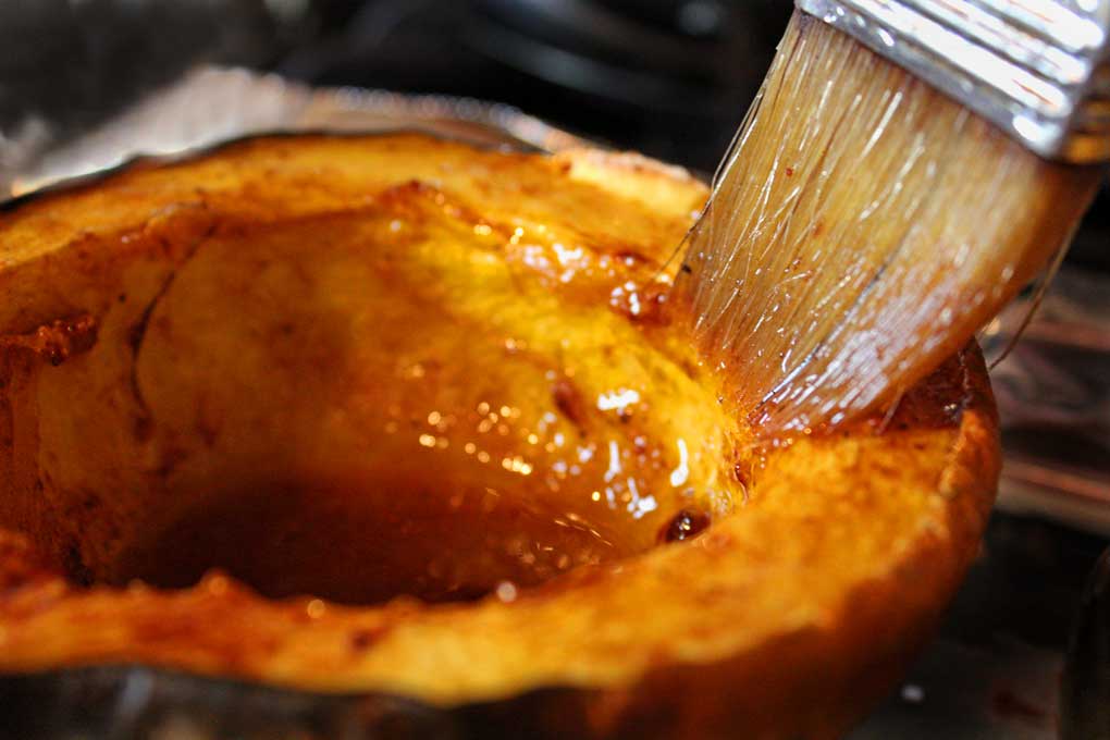 brushing acorn squash with buttery brown sugar and cinnamon