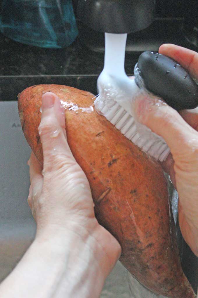 washing potato with vegetable brush