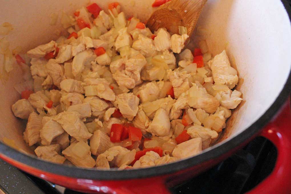 chicken, onion, bell peppers and garlic cooking in pot