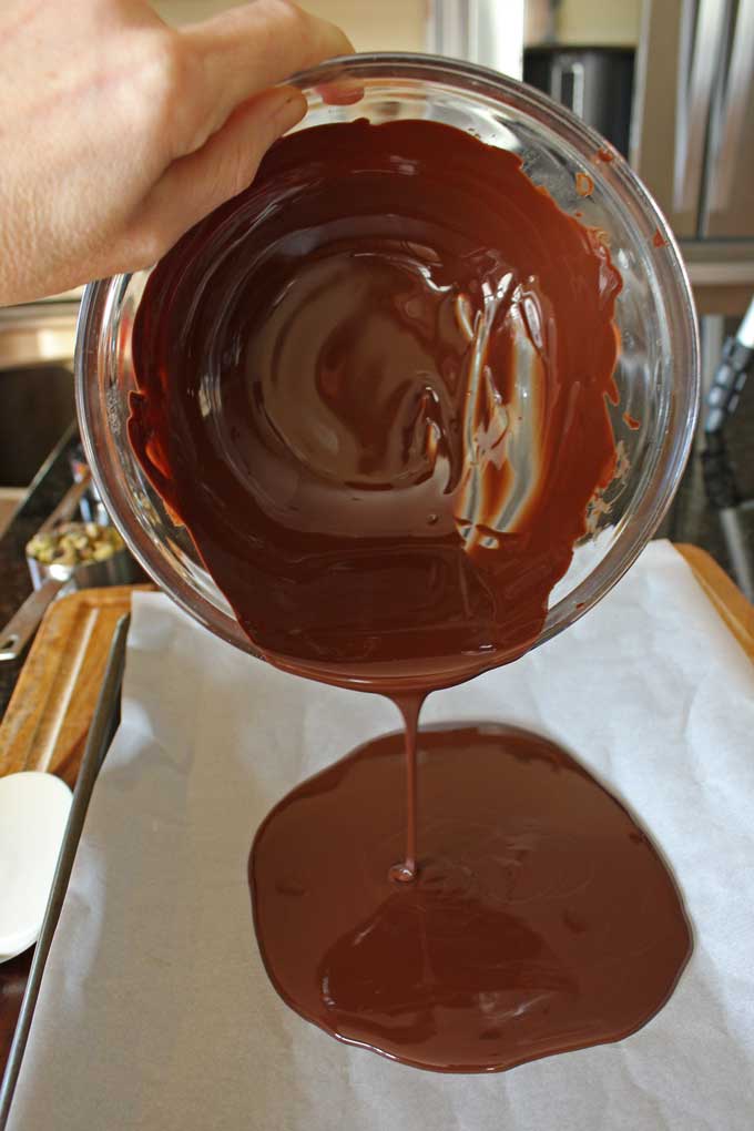 pouring chocolate onto rimmed baking sheet
