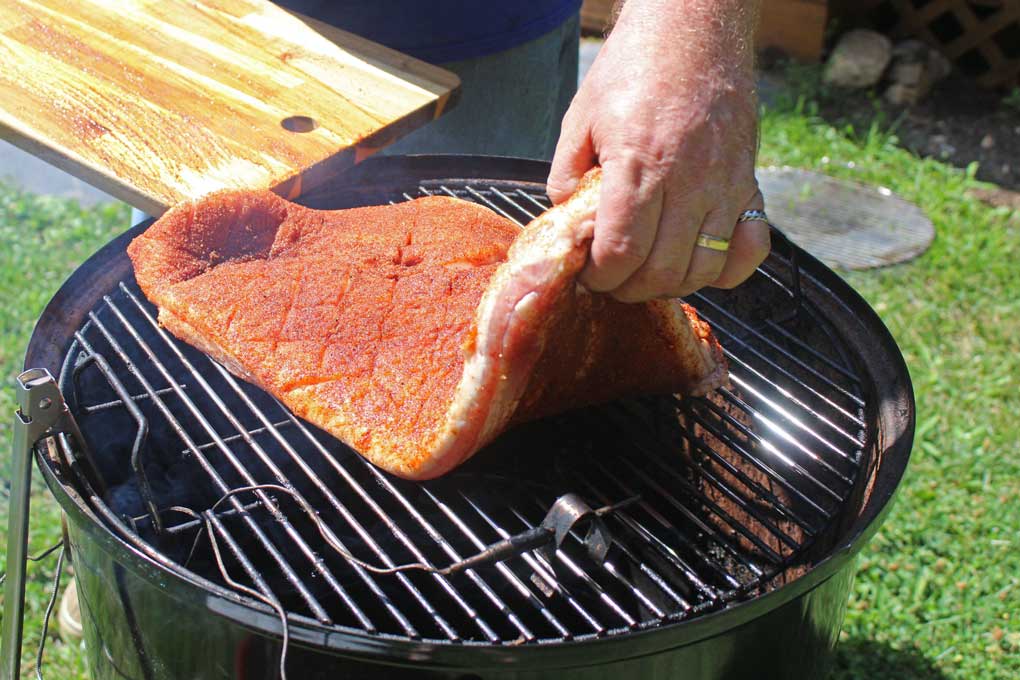 placing the pork belly on smoker