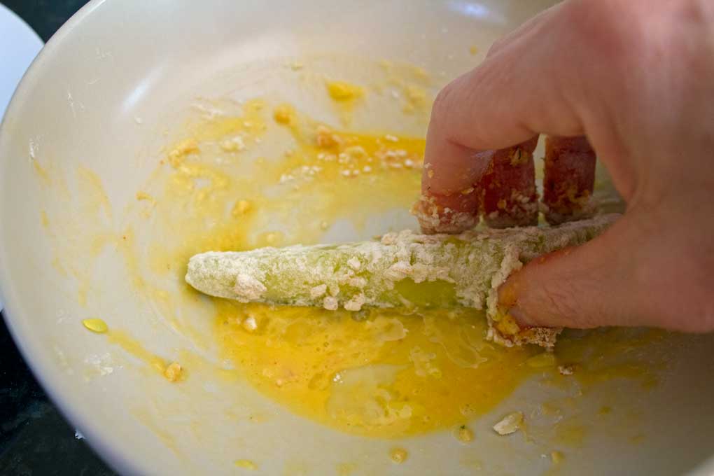 coating flour-covered pickle with egg