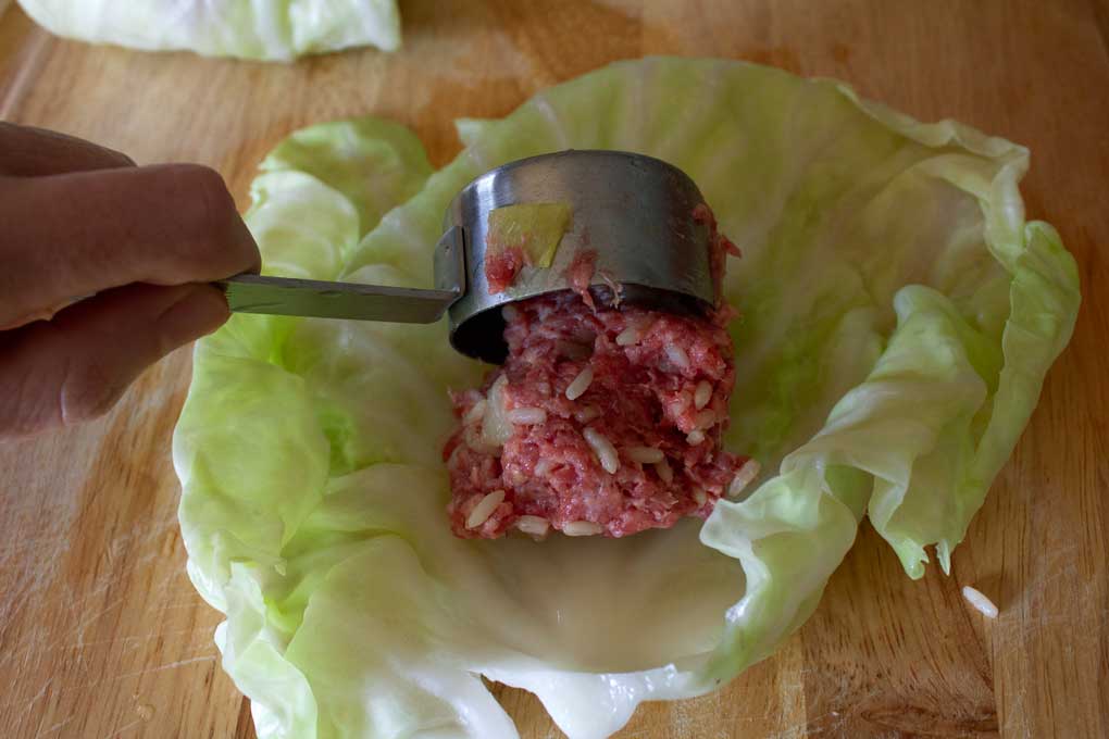 scooping beef mixture onto cabbage leaf