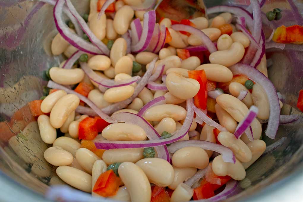 white beans, onions, red bell pepper and capers in bowl