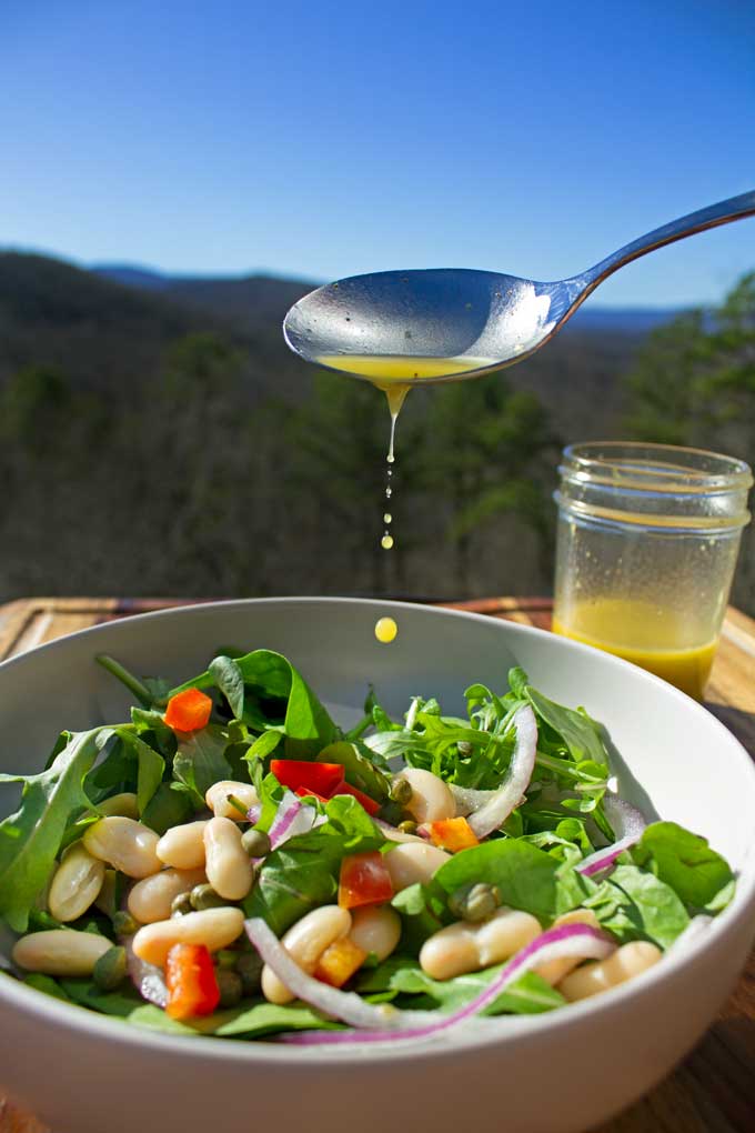 drizzling dressing onto salad with mountain view