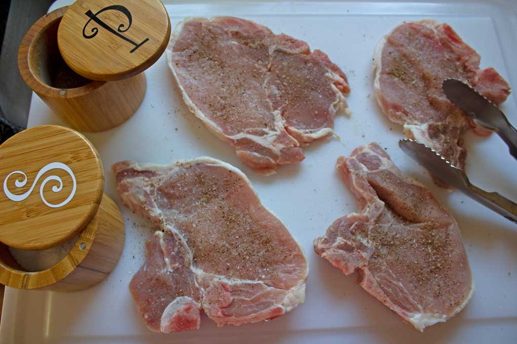 raw pork chops seasoned with salt and pepper