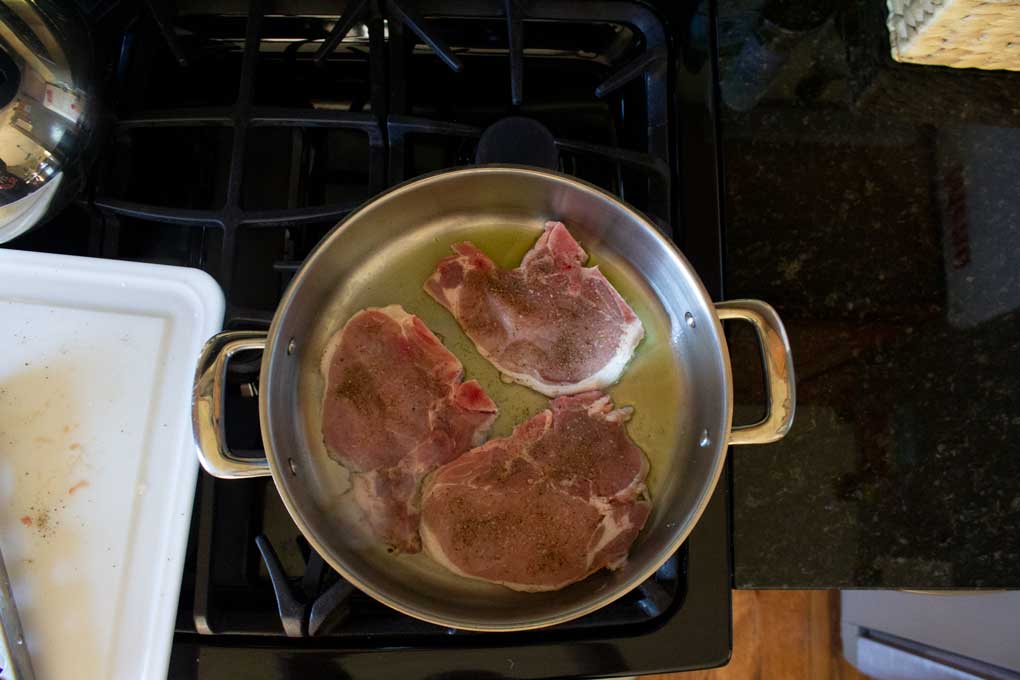 pork chops searing in pan