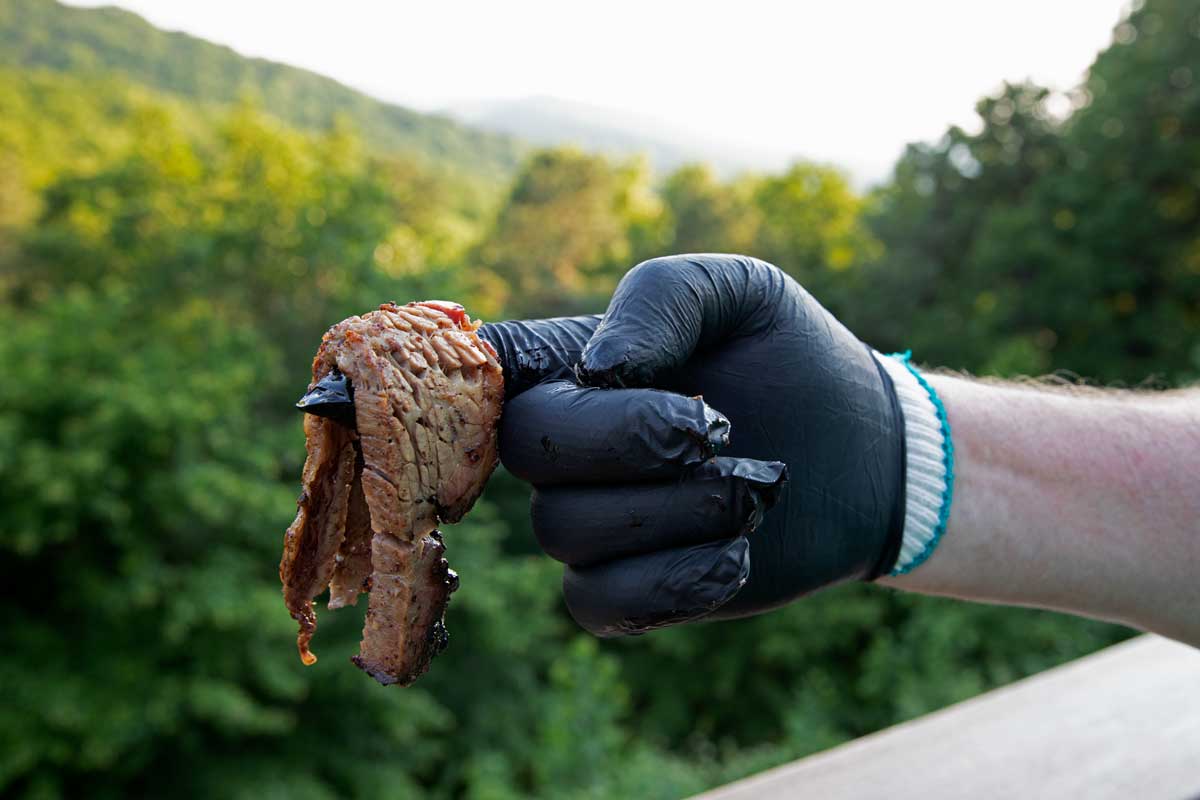 hand with cotton and rubber glove holding hot meat