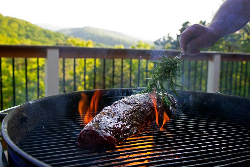 brushing hot flaming meat with herb brush and garlic butter