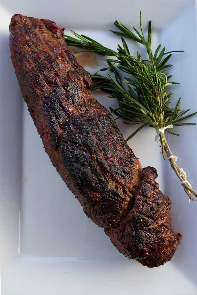 smoked beef tenderloin on a platter with herb brush