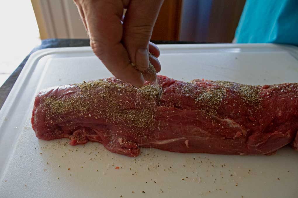 sprinkling dry rub on meat