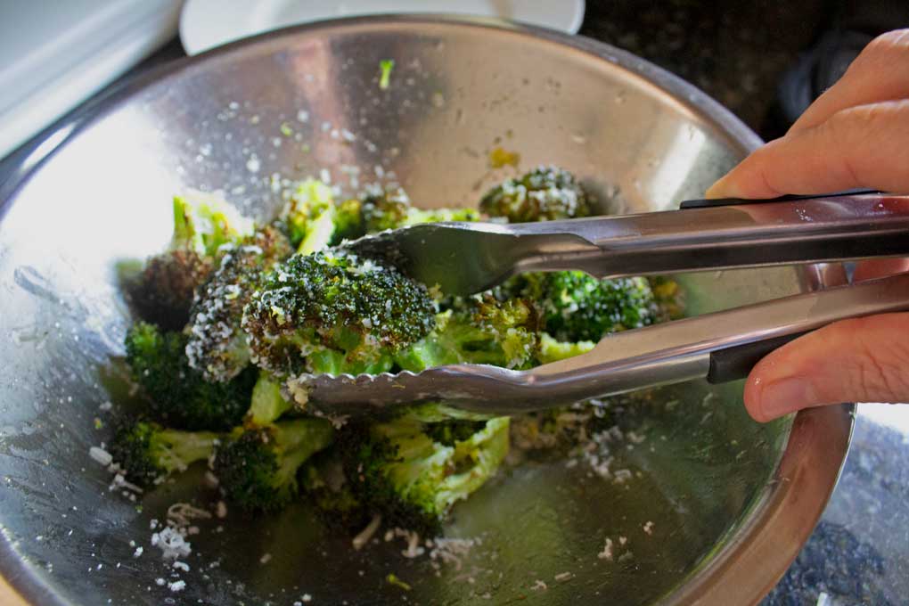 tossing air fryer broccoli with cheese and lemon zest