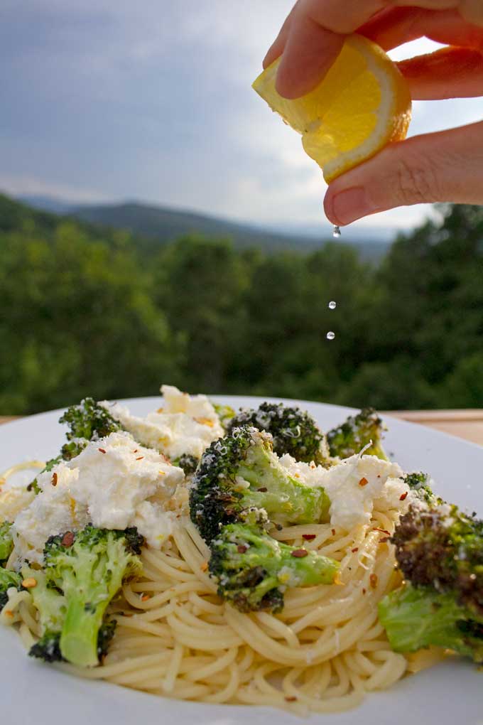 squeezing lemon juice onto air fryer broccoli with ricotta and pasta